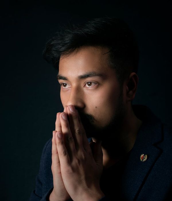 Profile of a focused man meditating in a dark room with a calm expression.